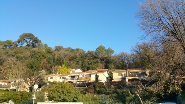 A hillside residential area with terraced houses, lush greenery, and a clear blue sky.