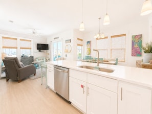 A modern kitchen with a dishwasher, a sink, and pendant lighting.