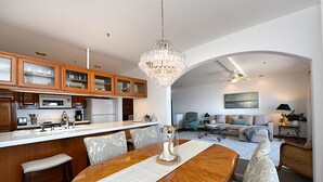 A spacious living area with a dining table, a chandelier, and a kitchen with wooden cabinets. - H881: Beautiful Townhouse style villa + CART+ 2 Private Balconies + King bed (Avalon)