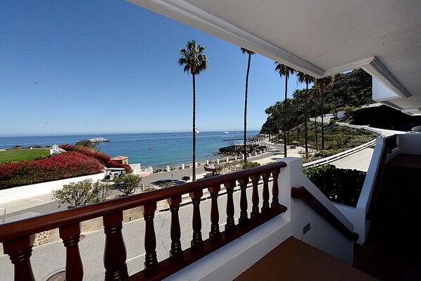 A balcony with a view of the ocean and a landscaped area with palm trees. - H881: Beautiful Townhouse style villa + CART+ 2 Private Balconies + King bed (Avalon)