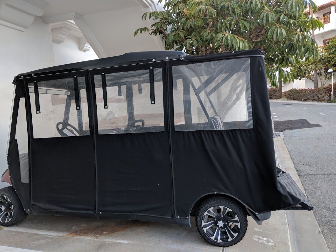 A black covered vehicle parked on a street.