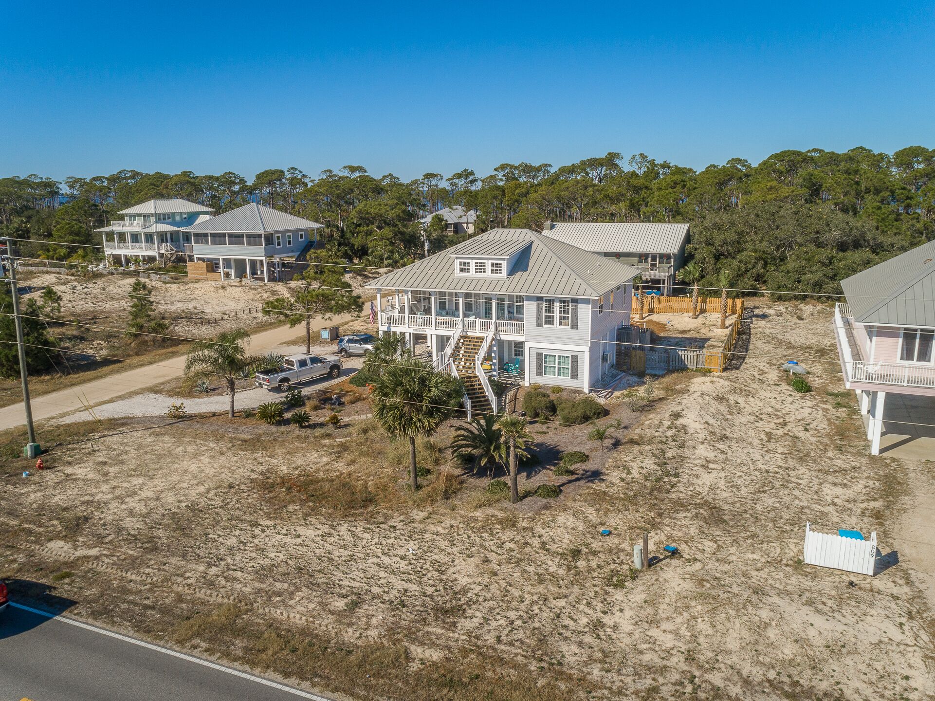 A coastal house with a large deck, multiple windows, and a staircase leading to a balcony.