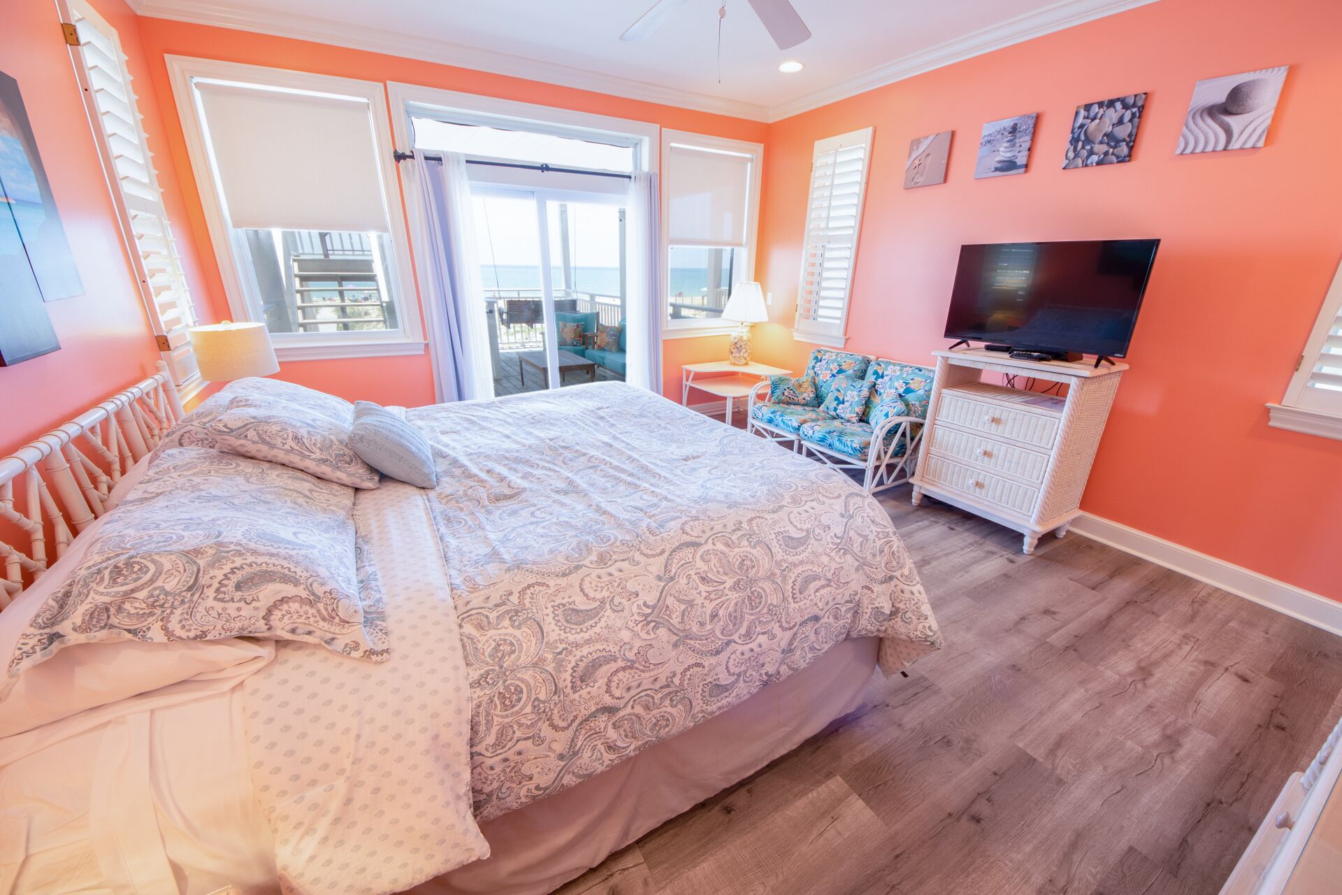 A bedroom with a large bed, a TV, and a balcony with a view.