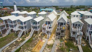 Un quartier résidentiel situé sur la côte, composé de plusieurs maisons à deux étages dotées de balcons, avec un phare en arrière-plan.