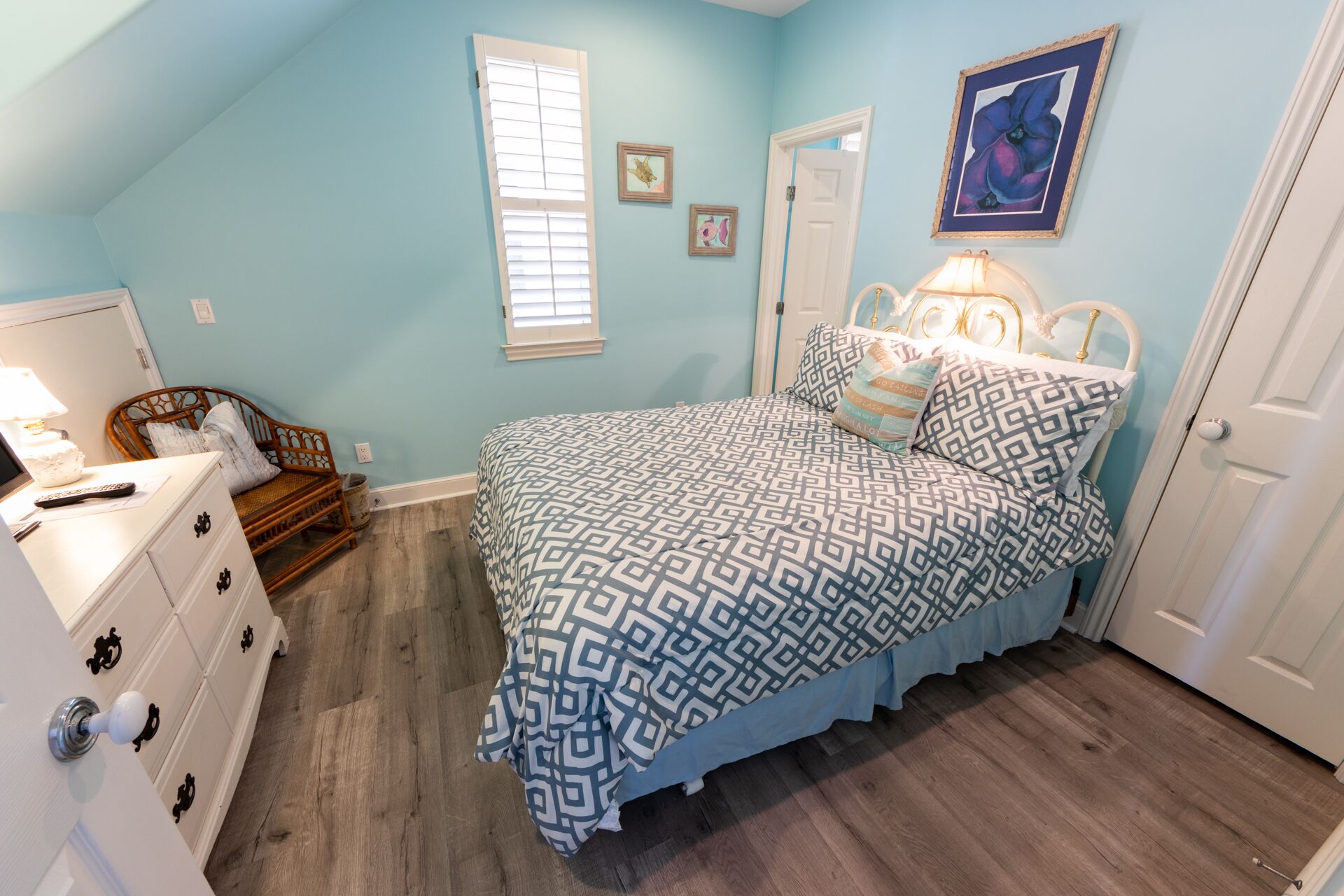 A bedroom with a bed, dresser, and a window.