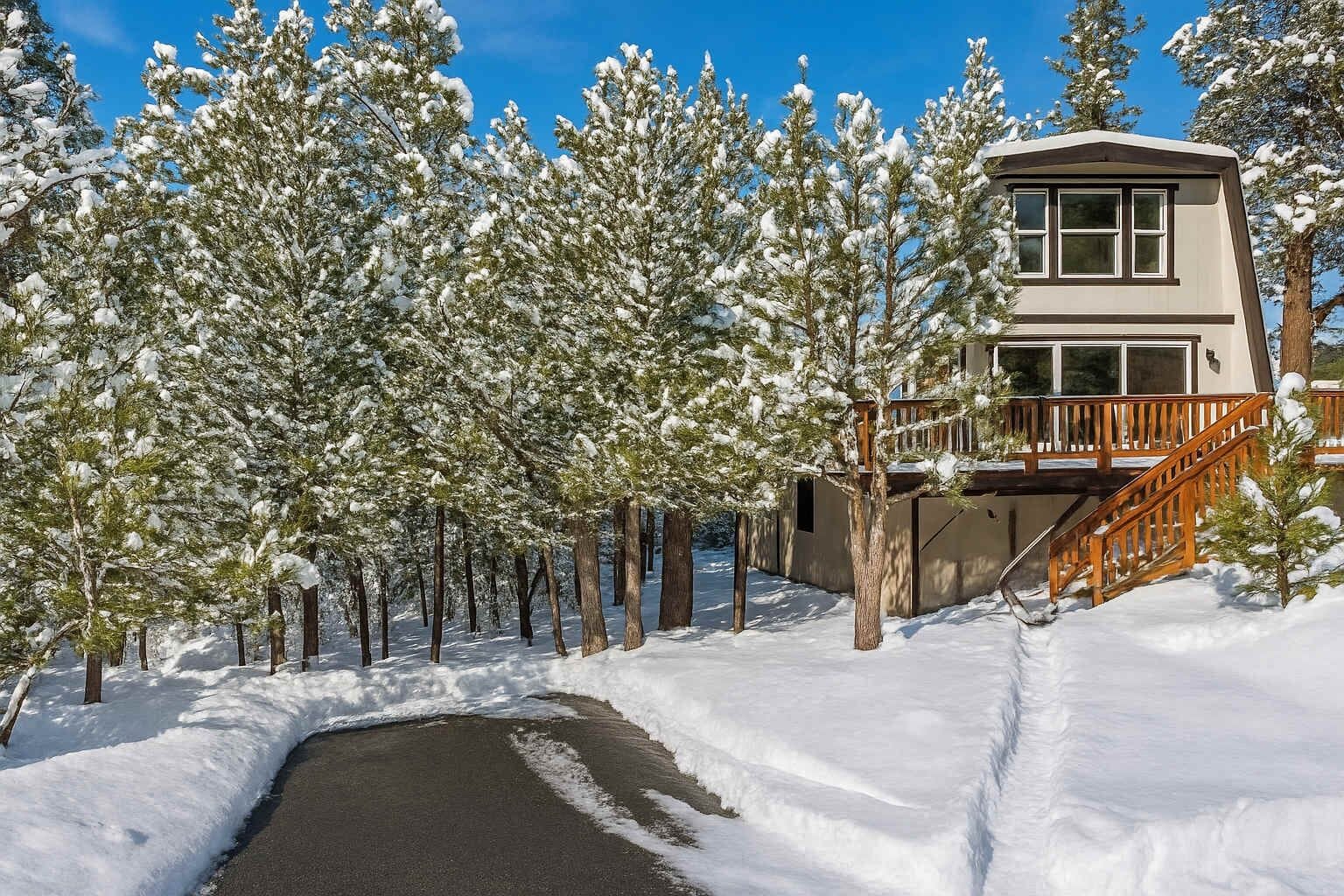 A two-story building with a wooden deck and a snow-covered landscape.
