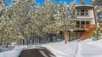 A two-story building with a wooden deck and a snow-covered landscape.