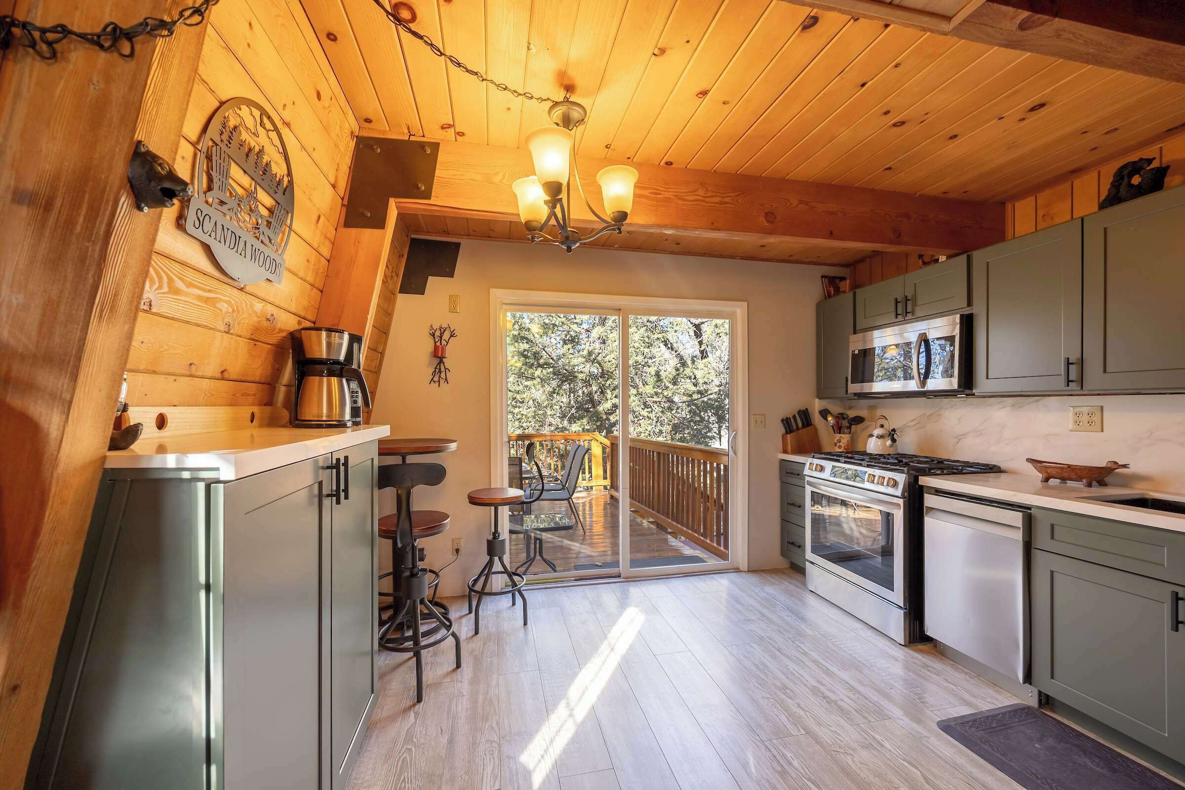 A kitchen with wooden walls, a chandelier, a coffee maker, and a view of the outdoors.