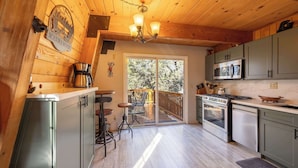 Una cocina con paredes de madera, una araña, una cafetera y vistas al exterior.