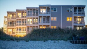 A beachfront hotel with multiple balconies and a sandy beach in the foreground. - OceanThyme @ Windsong, Ocean Front Newly Remodeled and Decorated (North Myrtle Beach)