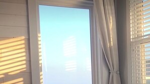 A room with a large window overlooking the ocean, a chair, and a view of the sea. - OceanThyme @ Windsong, Ocean Front Newly Remodeled and Decorated (North Myrtle Beach)