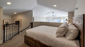 Ein Schlafzimmer mit einem Bett, einem Deckenventilator und Blick ins Freie durch ein Fenster.