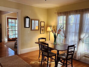 Enjoy meals in this cozy dining area with a wooden table and four chairs, surrounded by framed pictures and a vase with fresh flowers.