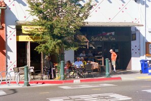 Situated on a lively street corner, this coffee shop offers a charming outdoor seating area with tables and chairs.