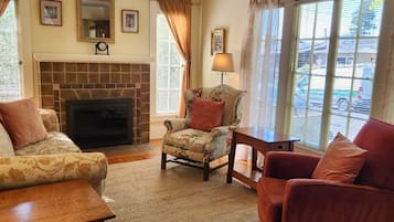 Relax in this inviting living room with a fireplace, comfortable seating, and a view of the street.