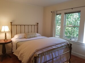 Cozy retreat with a single bed, bedside table, and window offering a view of lush greenery.