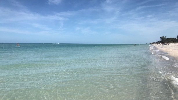 Ein Strand mit klarem, flachen Wasser und einem sandigen Ufer.