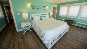 A bedroom with a bed, nightstands, a ceiling fan, and a window with blinds.