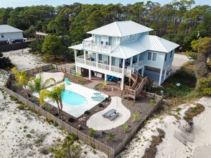A two-story house with a large deck, a swimming pool, and a sandy beach area. - August 2026 Big Savings!!! Outdoor Oasis, Family-Friendly, Dogs Ok! (St. George Island)
