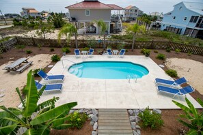A swimming pool with blue lounge chairs, a wooden deck, and a view of houses in the background. - August 2026 Big Savings!!! Outdoor Oasis, Family-Friendly, Dogs Ok! (St. George Island)