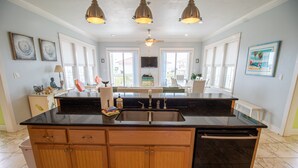 A spacious kitchen with a large island, wooden cabinets, and a black countertop. There are three pendant lights above the island, and a ceiling fan is visible.