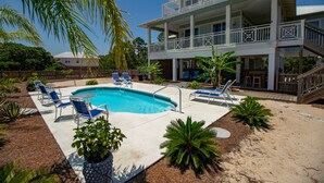 A two-story building with a pool, outdoor seating, and a wooden deck.