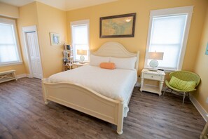 A bedroom with a large bed, a bedside table, a chair, a bookshelf, and a map on the wall. - August 2026 Big Savings!!! Outdoor Oasis, Family-Friendly, Dogs Ok! (St. George Island)