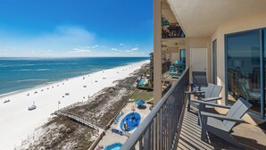 Un balcón con vista a la playa, una piscina y un área de comedor.