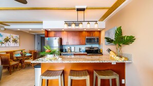 Een moderne keuken met houten kastjes, een granieten aanrecht en een centraal kookeiland met barkrukken.