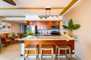 Cozinha moderna com armários de madeira, bancada de granito e uma ilha central com banquetas.