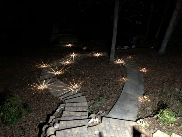 A spiral staircase with lights at the top, surrounded by a wooded area.