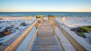 Une promenade en bois qui mène à une plage d’où l’on a une vue dégagée sur l’océan.