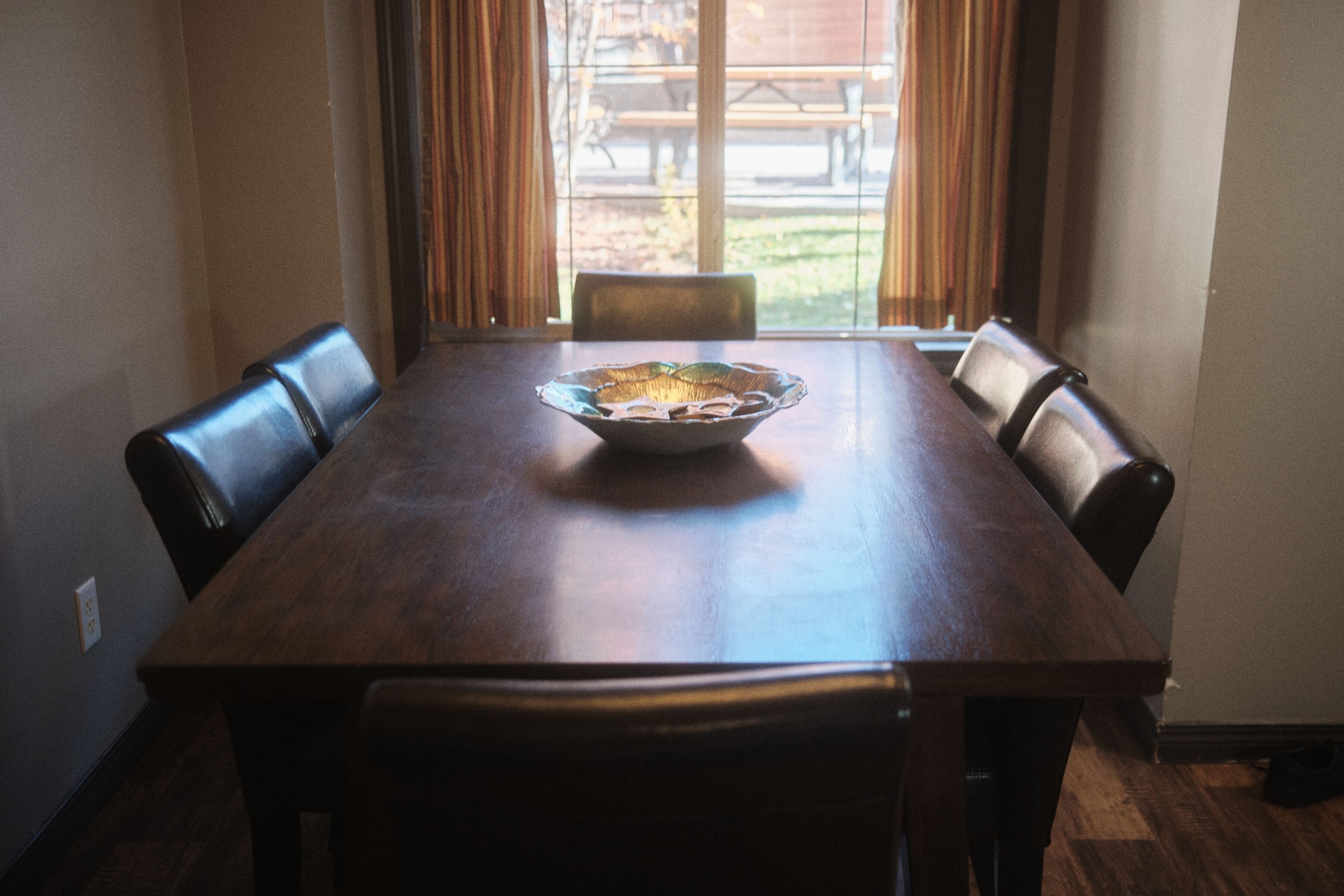 A dining table with a bowl in the center, surrounded by chairs.