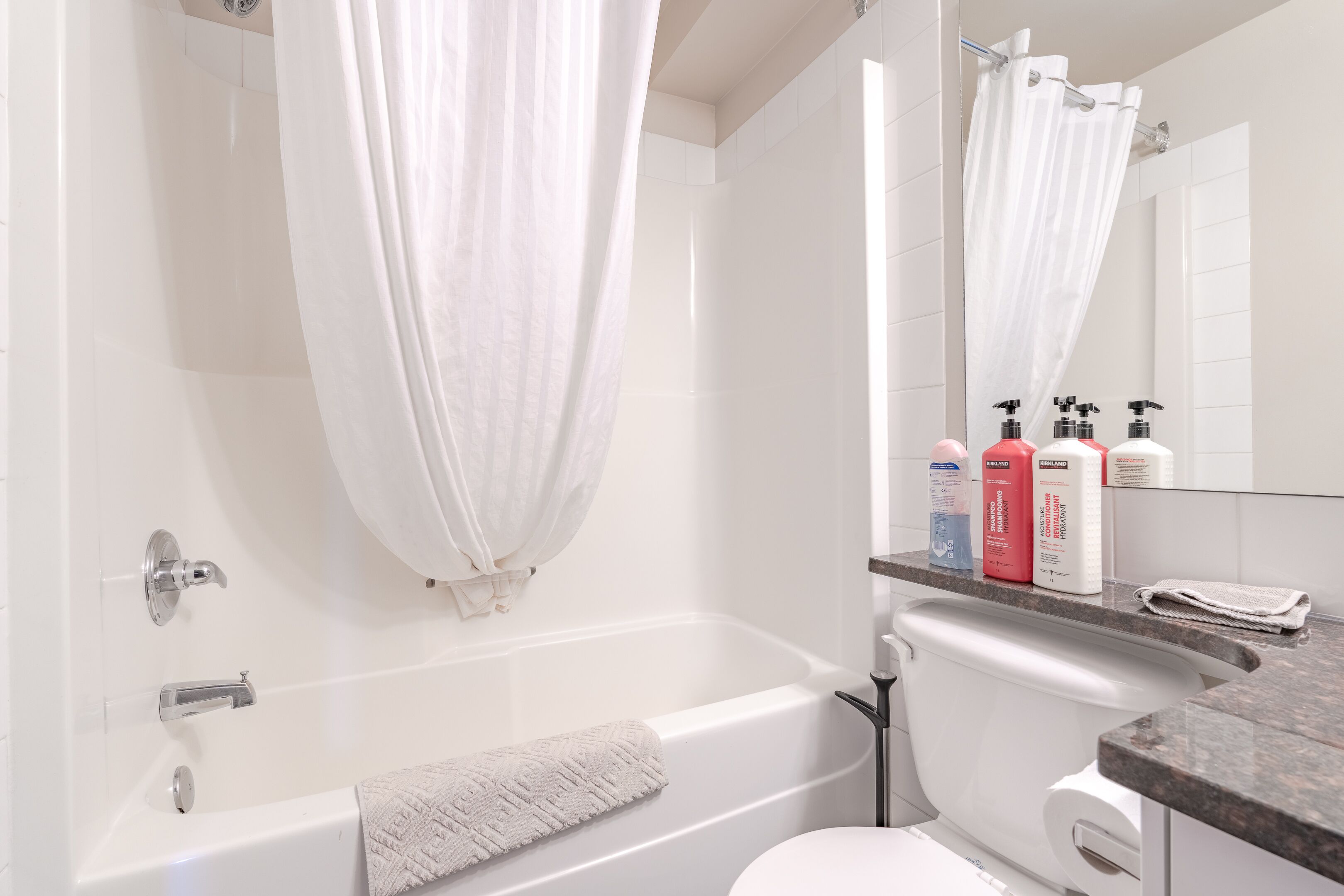 A modern bathroom with a bathtub, a toilet, and a shower area.