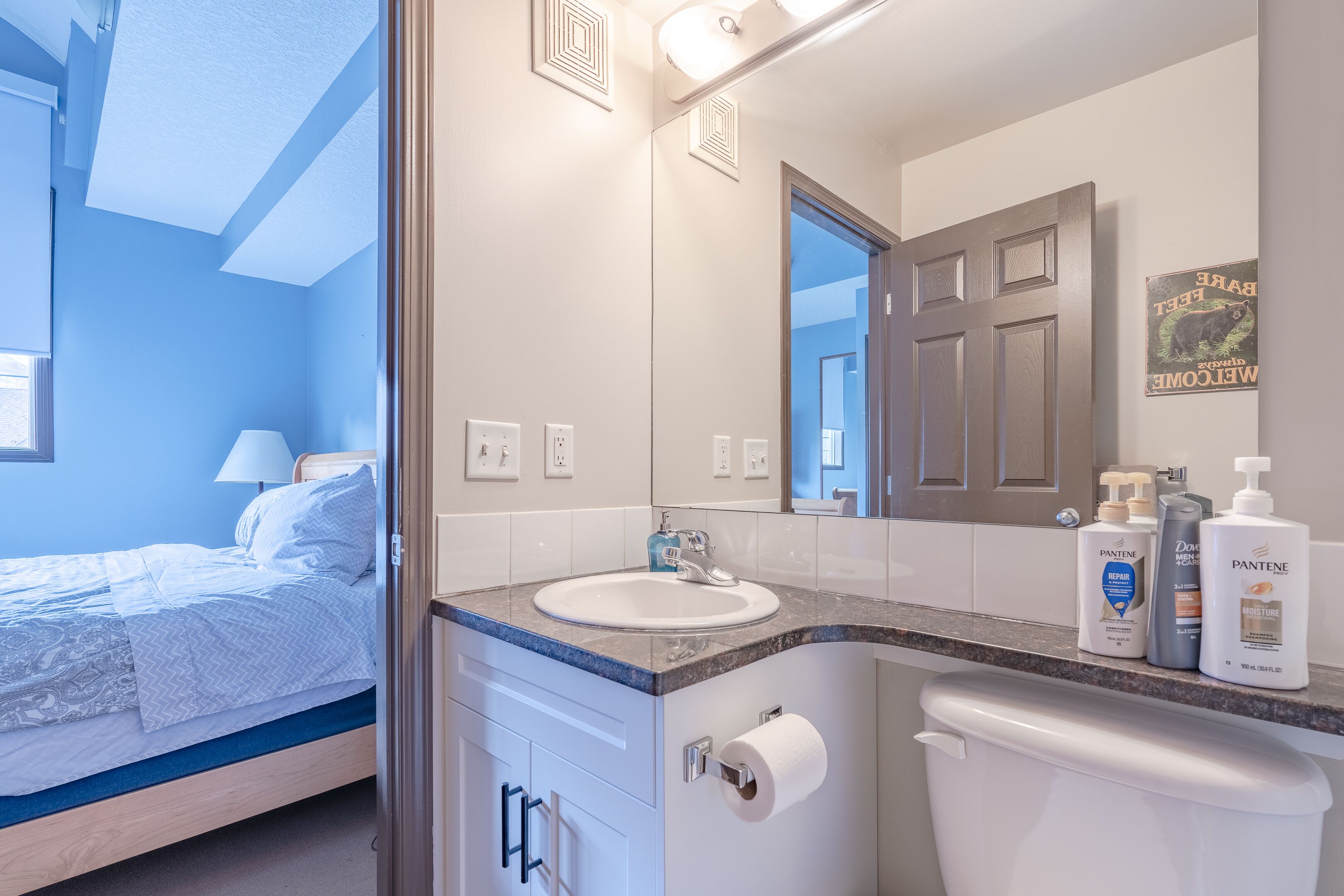 Een moderne badkamer met een wit wastafel, spiegel en toilet. Er staan Pantene producten op het aanrecht.