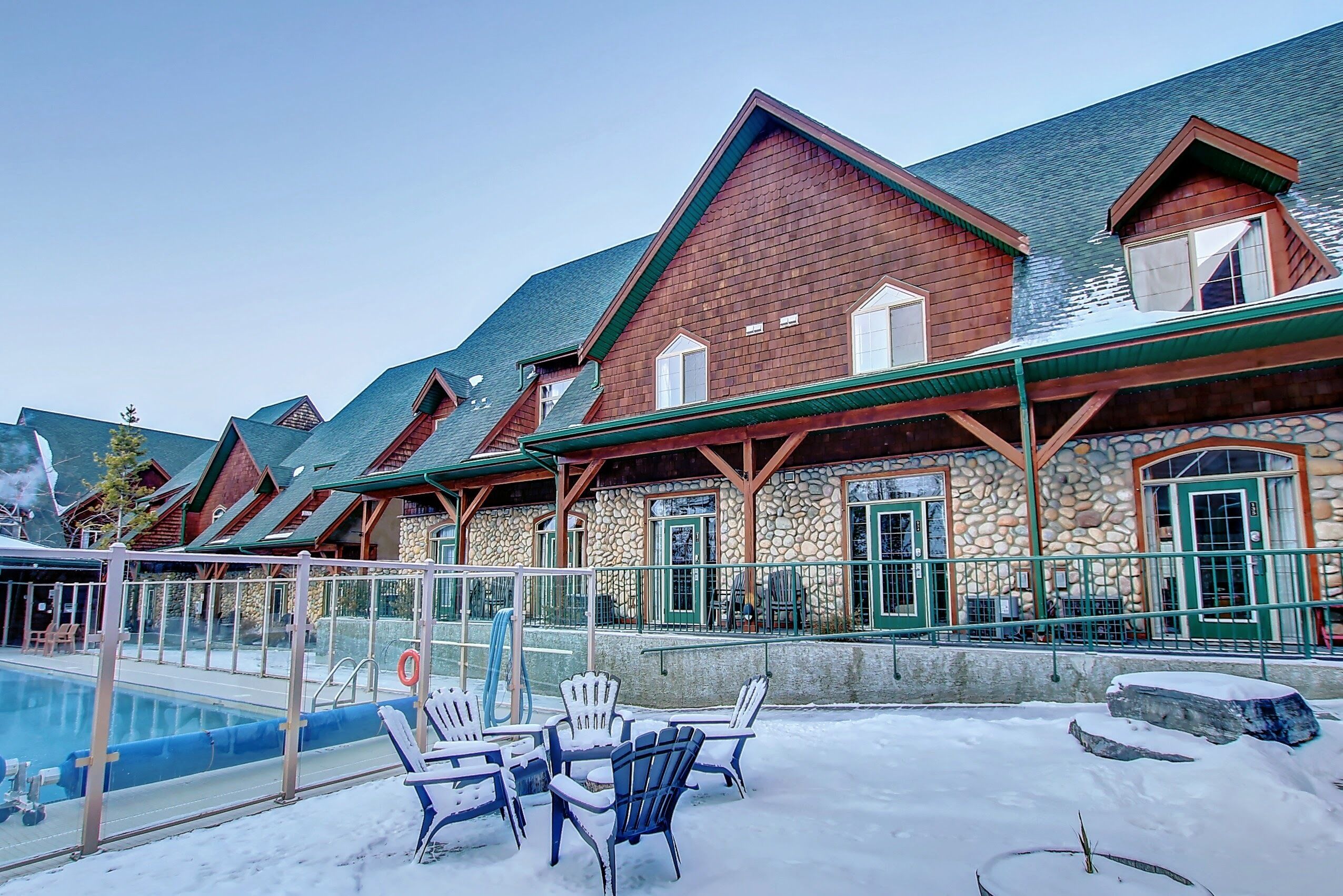 A stone building with a pool and outdoor seating.