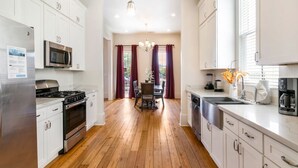 Een moderne keuken met witte kasten, roestvrijstalen apparatuur en een houten vloer.