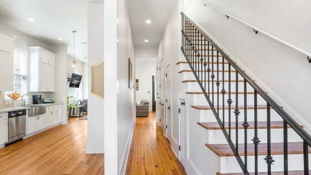 Een moderne keuken met witte kasten, roestvrijstalen apparatuur en een houten vloer.