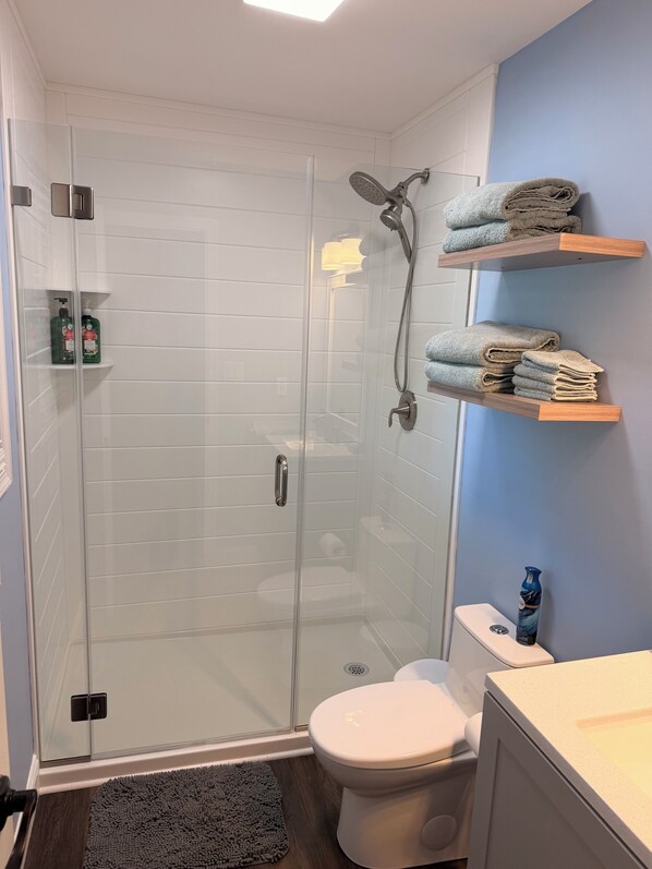 A bathroom with a glass-enclosed shower, a toilet, and a sink.