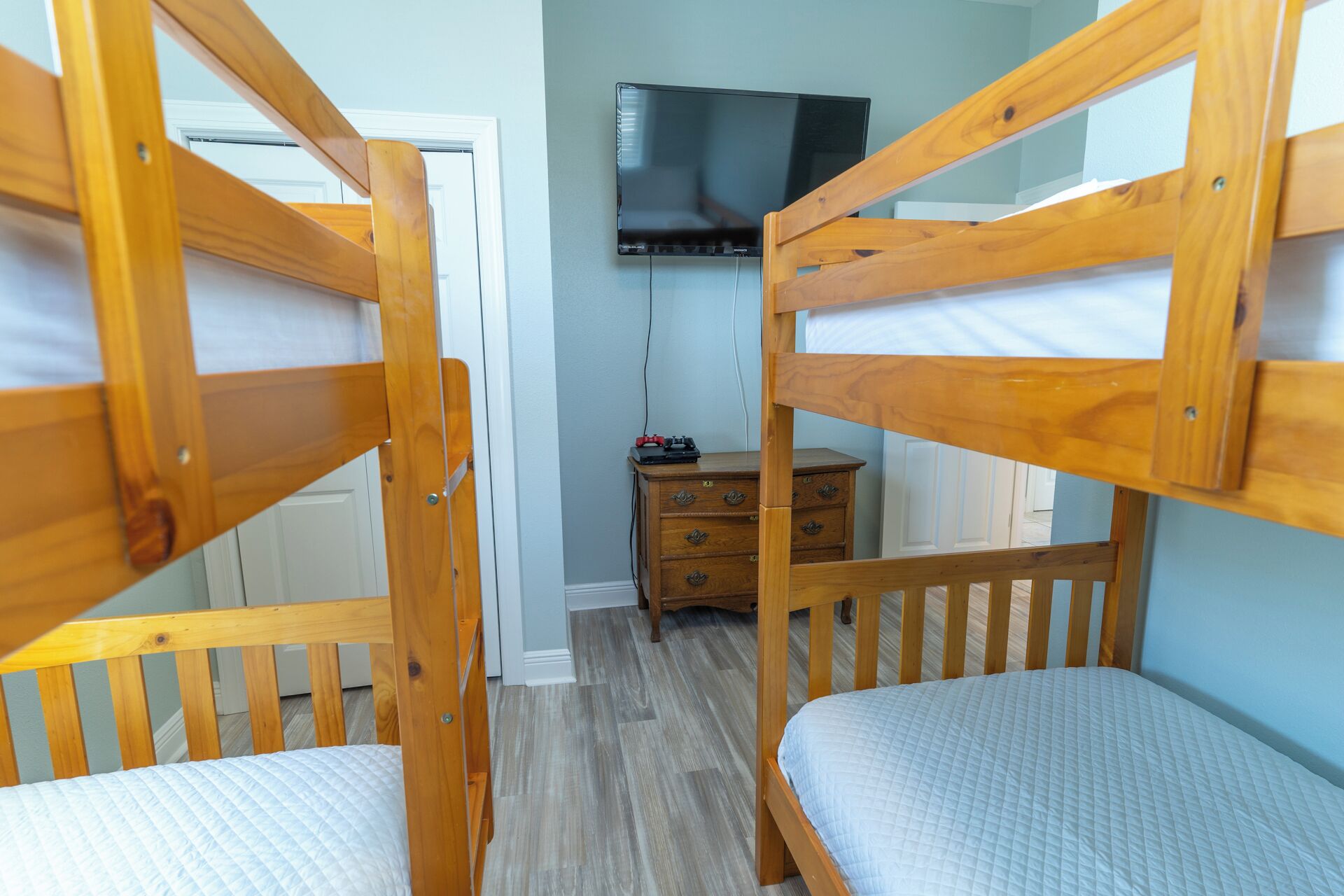 A room with bunk beds, a television, a dresser, and a door.