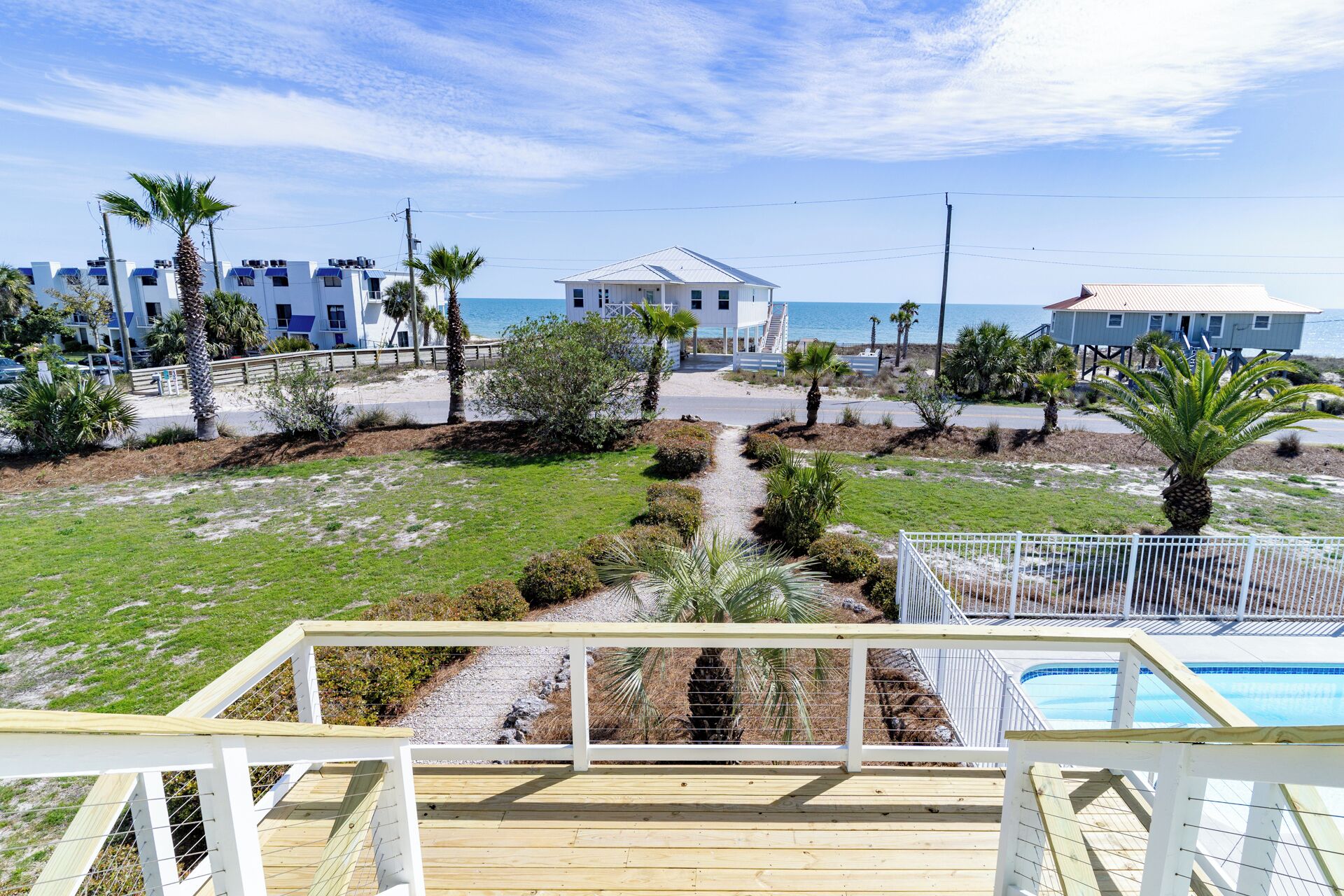 A beachfront property with a wooden deck, a swimming pool, and a view of the ocean.
