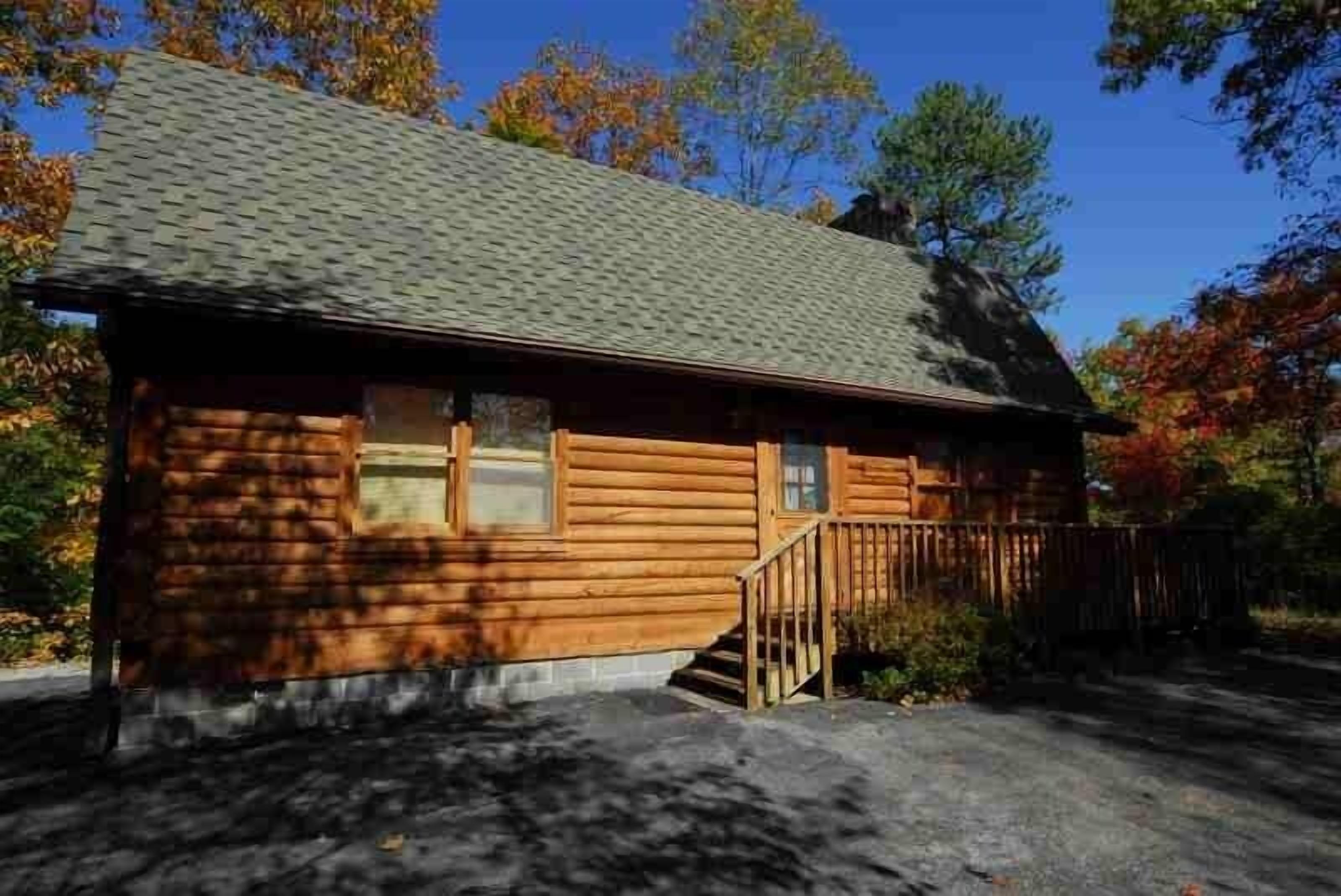A log cabin with a sloped roof, a front porch, and a small staircase leading to the entrance.