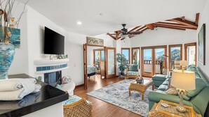 A spacious living room with a fireplace, green sofa, and a view of the outdoors.