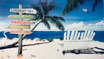 A beach scene with a wooden signpost listing beach names and a white beach chair.