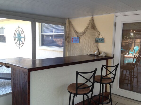 A reception area with a wooden counter, two bar stools, a decorative wall with a star emblem, and a sign that says "RELAX".
