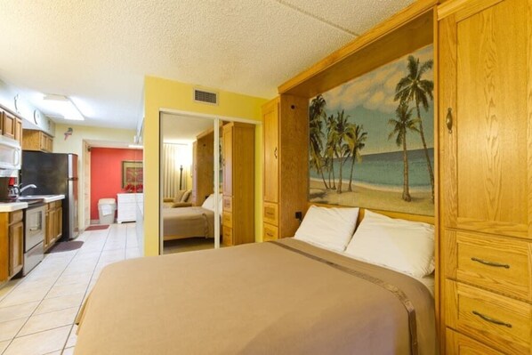 Ein Schlafzimmer mit einem Bett, einem Holzschrank und einem Bild im Strandhausstil.