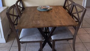 A dining table with four chairs, a decorative plate, and a wall-mounted light fixture. - Oceanfront Studio, sleeps 4 -Private balcony, pool, hot tub, BBQ (South Padre Island)