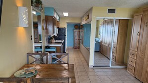 A kitchen with wooden cabinets, a dining table with chairs, and a tiled floor. - Oceanfront Studio, sleeps 4 -Private balcony, pool, hot tub, BBQ (South Padre Island)