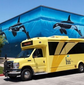 Ein gelber Bus mit der Aufschrift 'FREE RIDES' und '40' vorne, geparkt vor einem Gebäude mit einem Wandbild von Orcas.