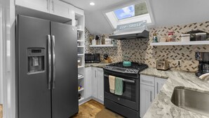 Une cuisine moderne équipée d’un réfrigérateur, d’une cuisinière, d’un four à micro-ondes et d’une lucarne au-dessus de l’évier.
